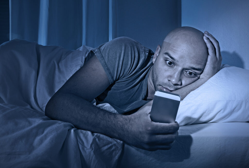 Man in bed starring at his phone