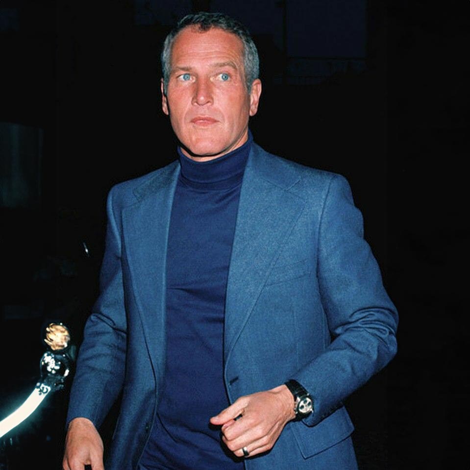 Paul Newman wearing a navy suit and a blue pullover