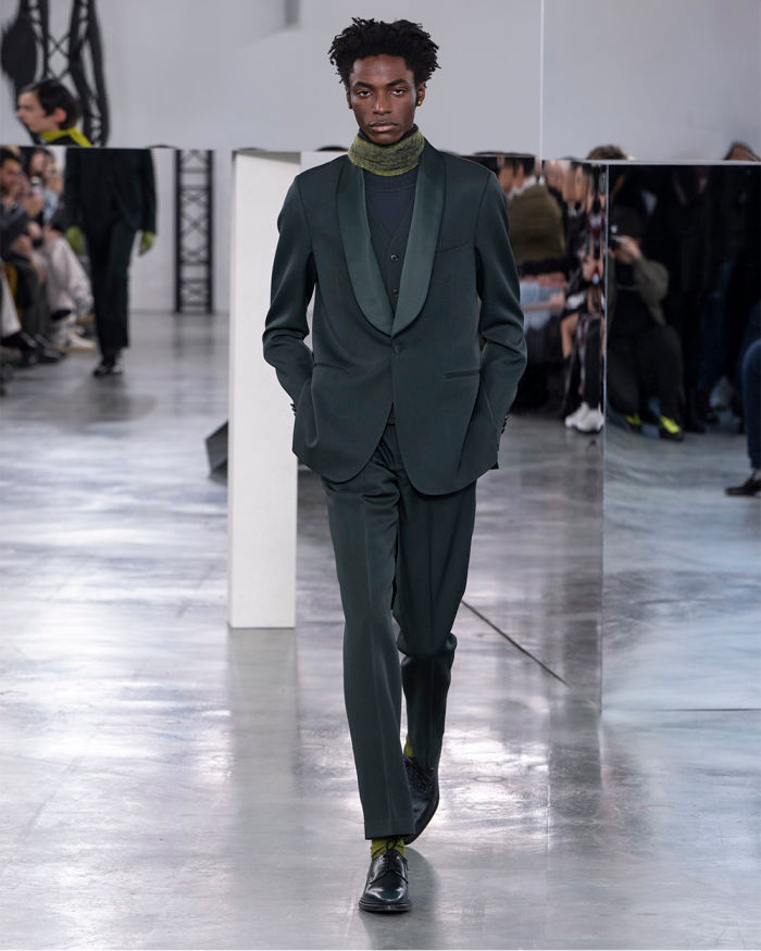 Model walks in a green suit with a scarf