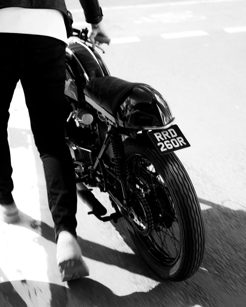 Man pushing motorcycle along road