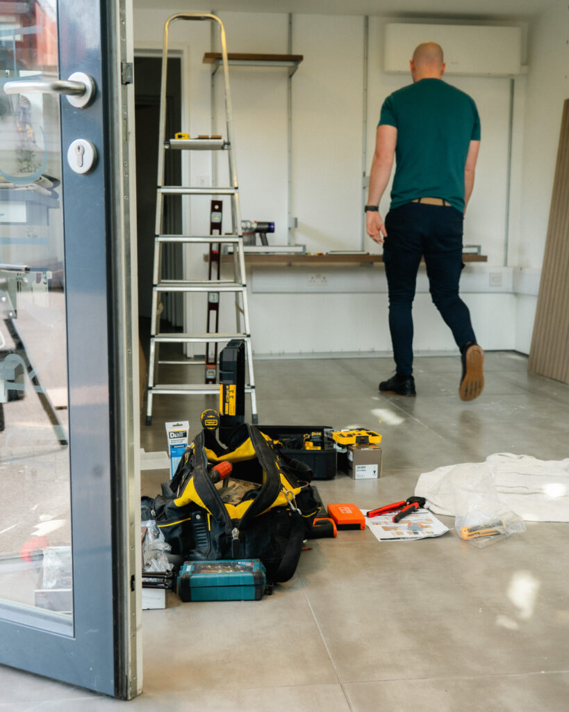 Image of man walking away from camera with tool bag in foreground.