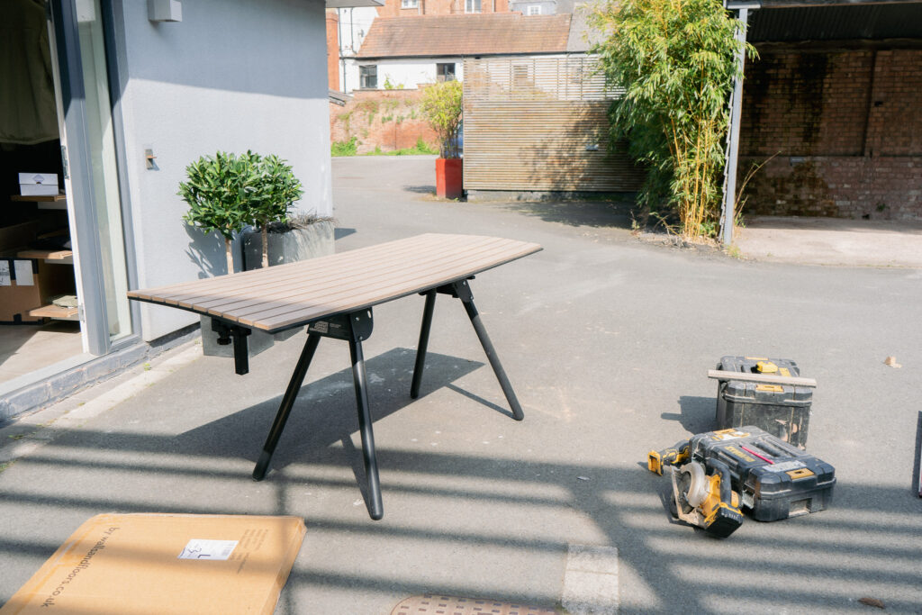 A wood cutting bench with a panel placed on top surrounded by tools.