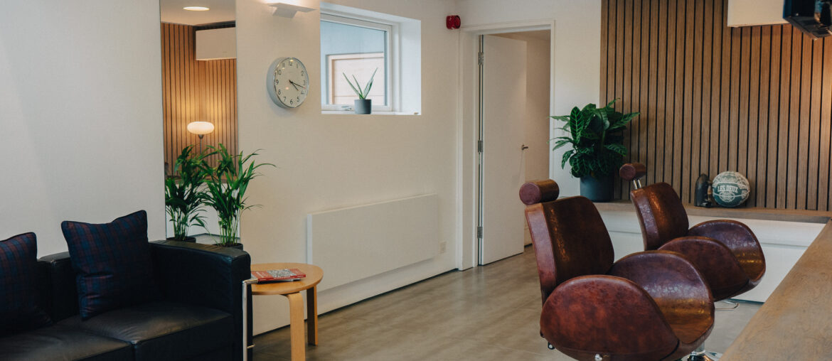 An image of barbershop chairs with a sofa and side table in shot.