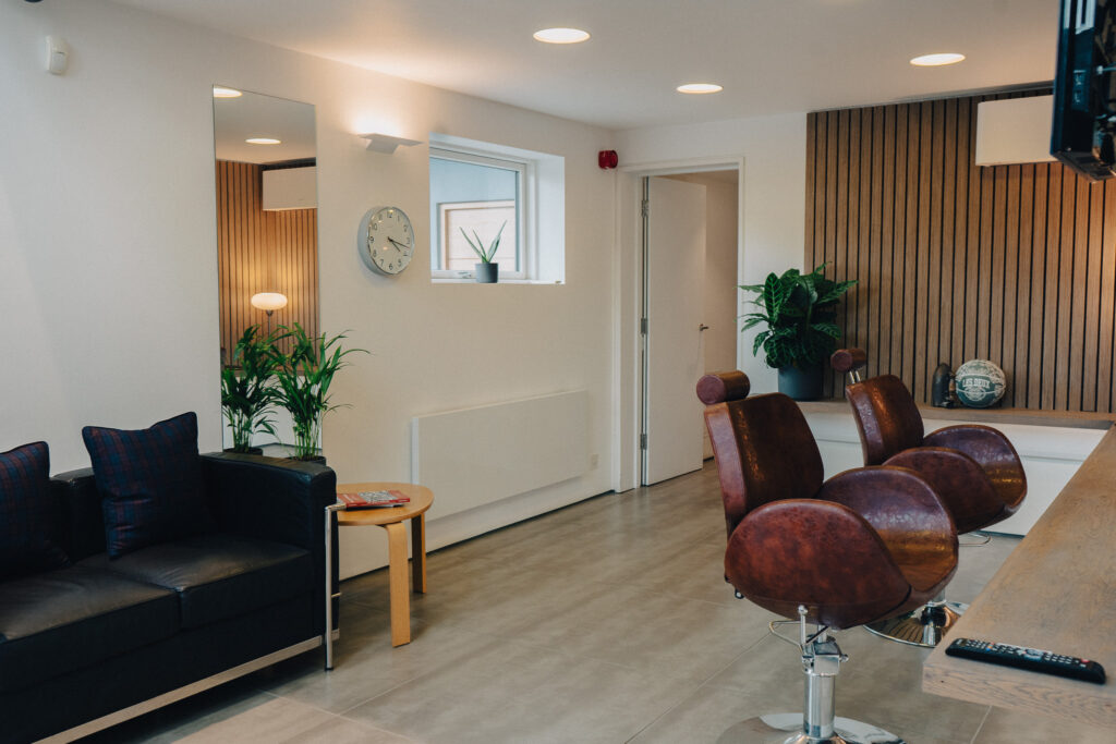 Image of barbershop chairs, with a sofa and side table.