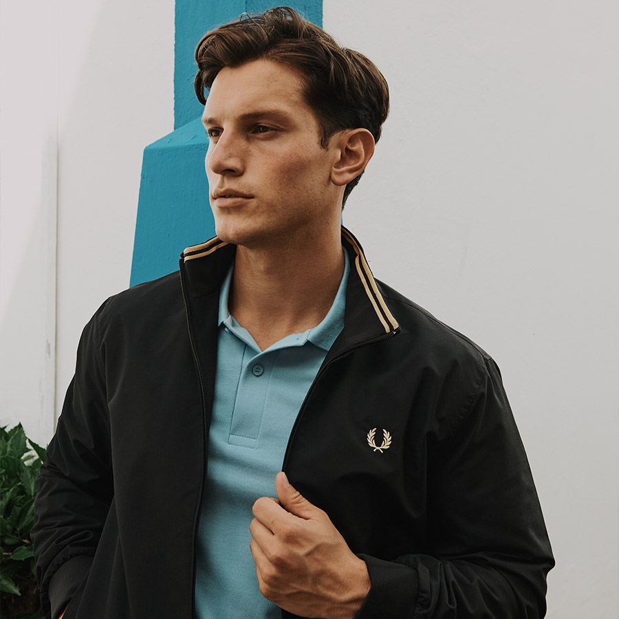 A man posing for a photo in a jacket and polo shirt