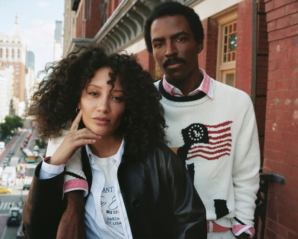 A smartly dressed man and woman pose for a photo on a balcony.