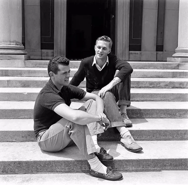 Two smartly dressed men sat on steps in front of a building