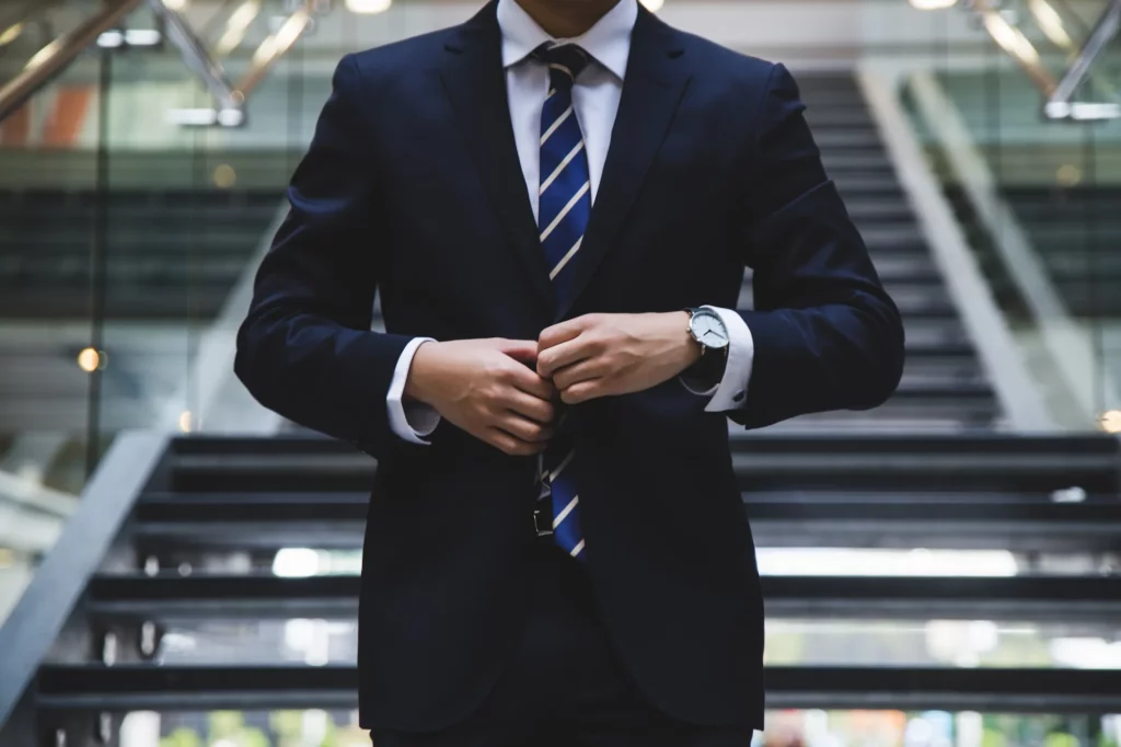 A closeup image of a man fastening the buttons on his suit.