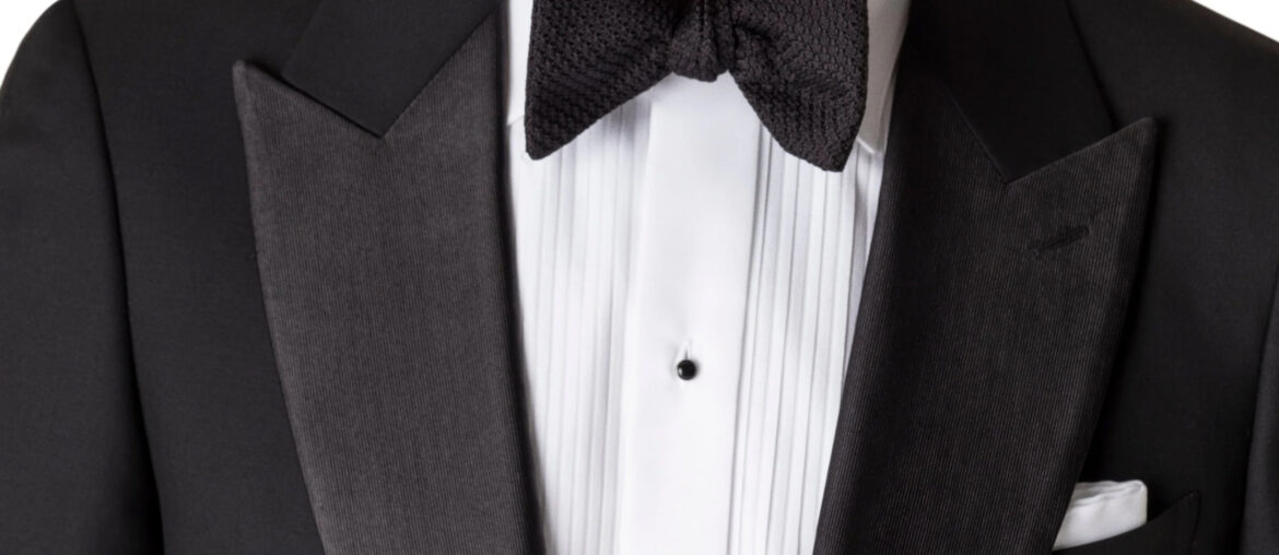 A close-up image of a man's chest wearing a suit with a black bow tie