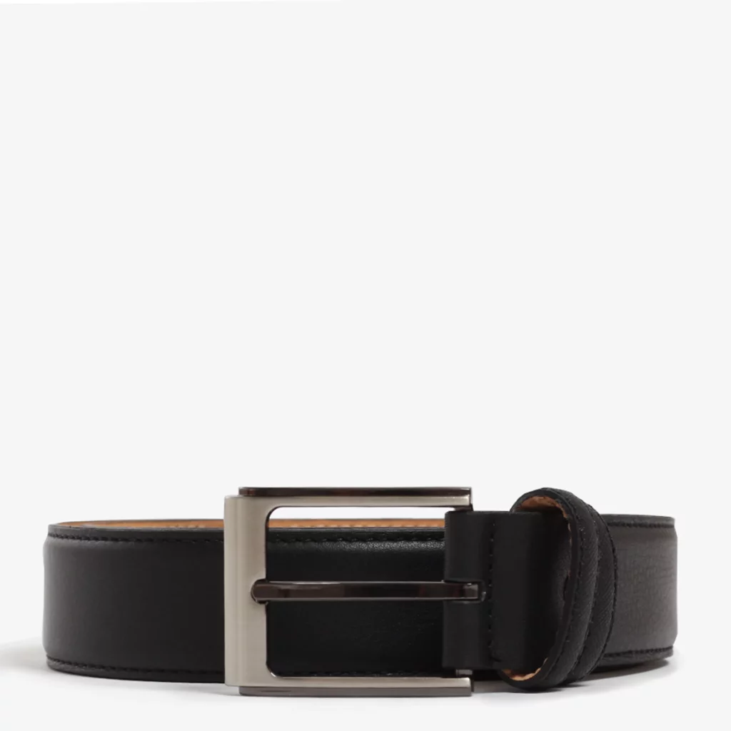 A closeup image of a rolled up black belt against a light grey background